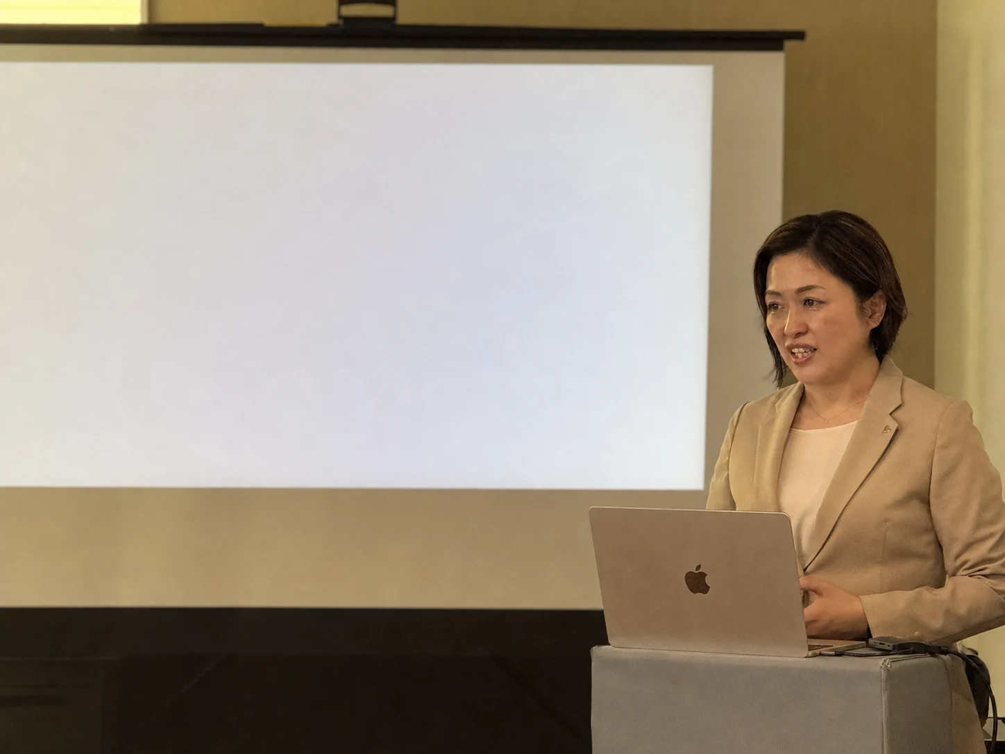 スクリーンの前で講演する、あきやフリースクールたね代表の菊池あかり